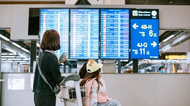 Indenização por overbooking: mulher e criança olhando painel de aeroporto