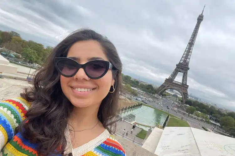 Mulher sorrindo em frente a torre Eiffel