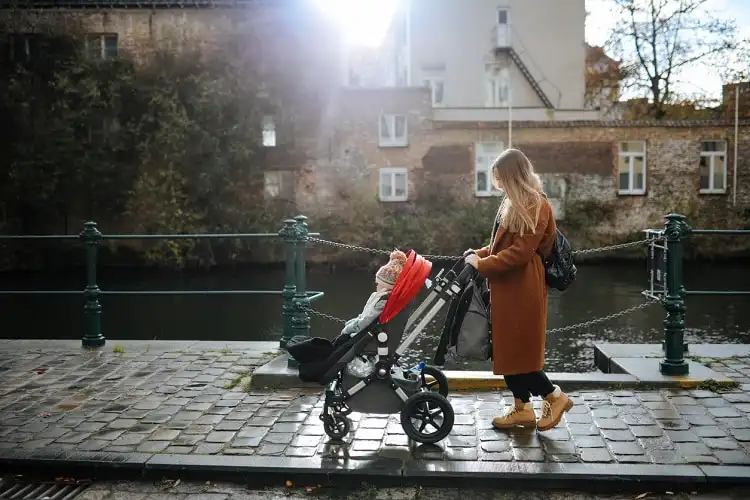Mulher carregando carrinho de bebê na beira de rio na Bélgica