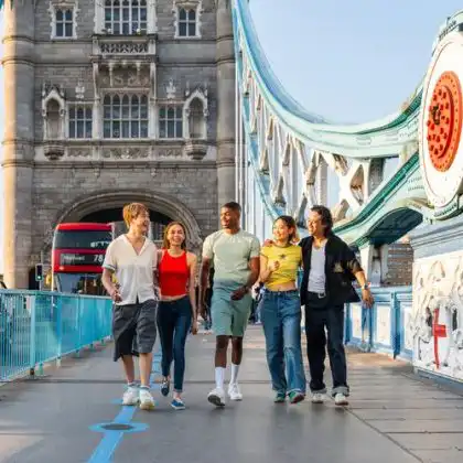 Grupo de estudantes fazendo intercâmbio na Europa e caminhando na Tower Bridge.