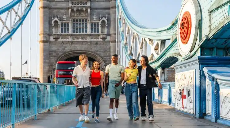 Grupo de estudantes fazendo intercâmbio na Europa e caminhando na Tower Bridge.