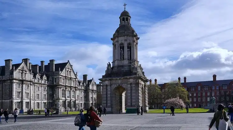 Turistas passeando em frente à Trinity College em Dublin