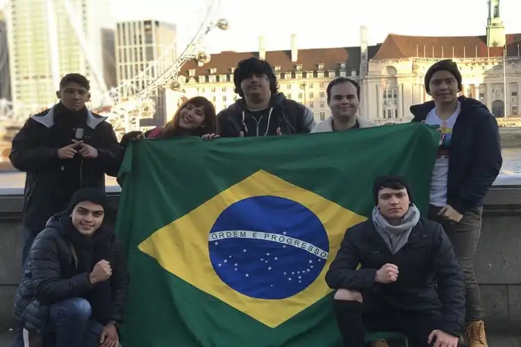 Grupo de estudantes de intercâmbio na Inglaterra segurando a bandeira do Brasil