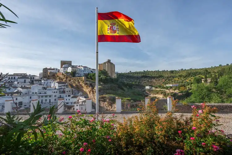 Bandeira da Espanha ao vento com pueblo espanhol ao fundo