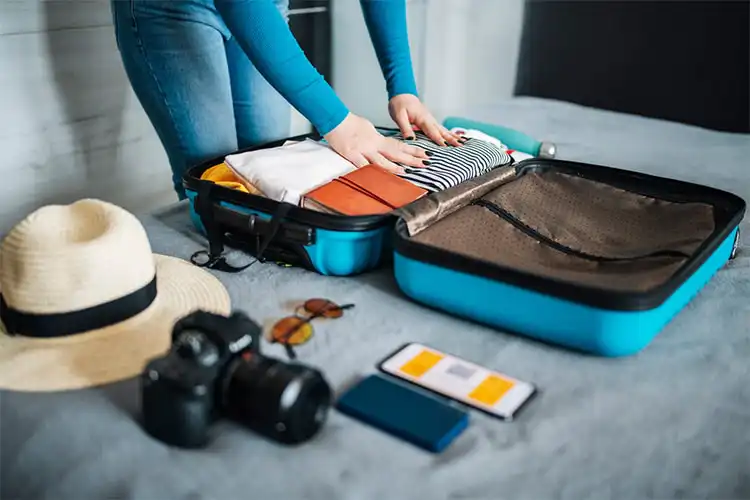 Mãos de mulher arrumando mala de viagem