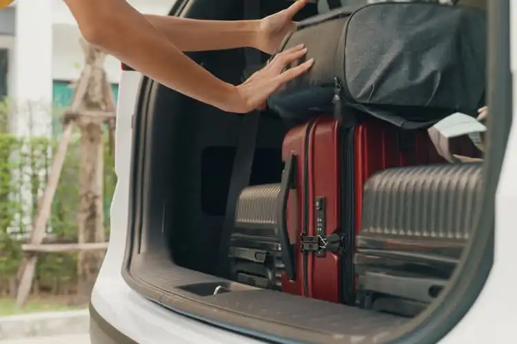 Viajante colocando malas no porta-malas do carro