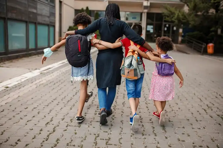 Mãe com três crianças na frente de escola na Bélgica.