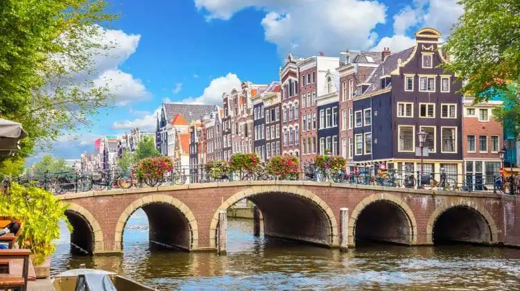 Vista de um canal em Amsterdam com alguns prédios no fundo