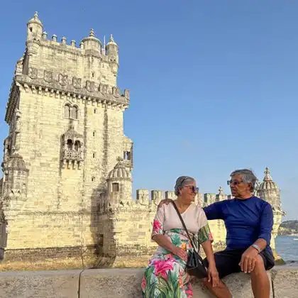 Casal aposentado em frente à Torre de Belém, Portugal.
