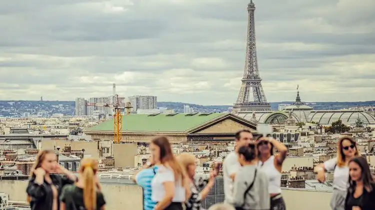 Turistas desfocados em primeiro plano com Torre Eiffel ao fundo