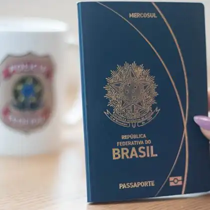 Mão feminina segurando novo passaporte brasileiro