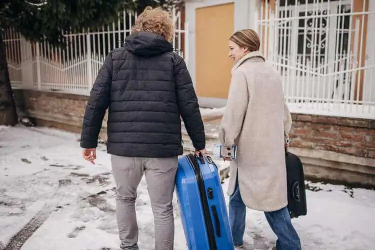Homem e mulher andando em um dia de inverno carregando uma mala de viagem para europa