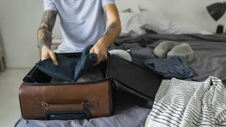 Homem fechando malas antes de viajar para Europa.