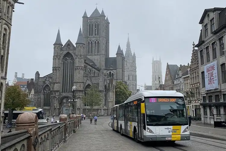 Foto de ônibus na Bélgica, na frente de igrejas históricas. 