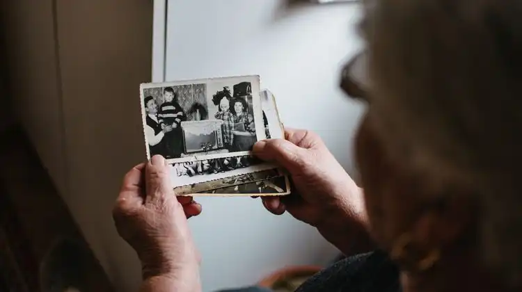 Senhora segurando uma fotografia em preto e branco tentando descobrir a origem do sobrenome