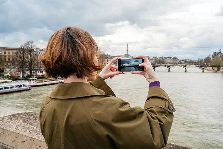 Mulher tirando foto durante viagem, com smartphone.