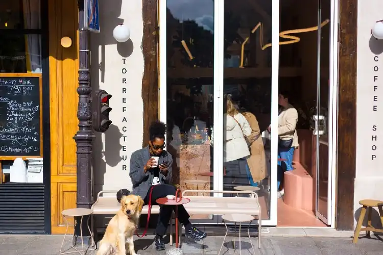 Mulher com cachorro em frente a um café.