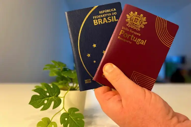 Mão segura os passaportes brasileiro e português