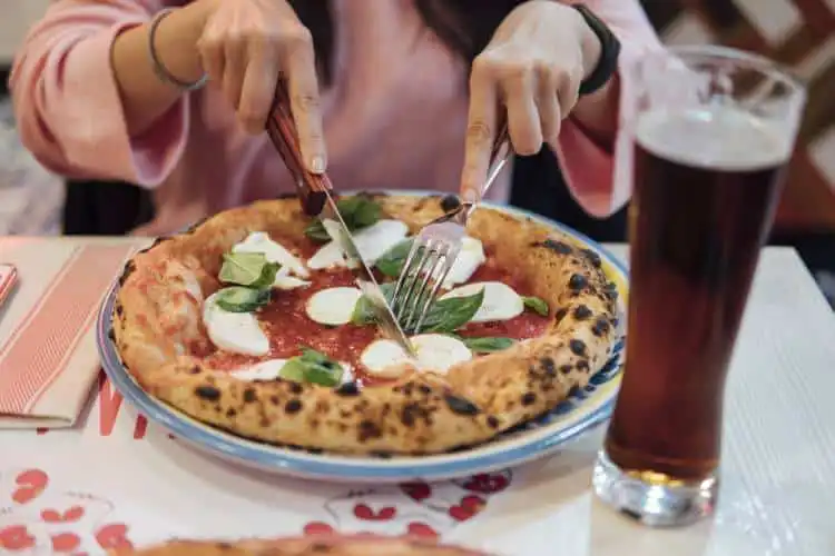 Turista cortando pizza na Itália