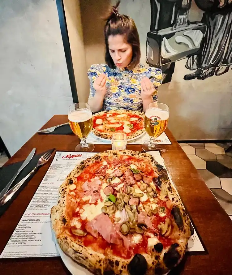 Roberta em frente a duas pizzas servidas à mesa