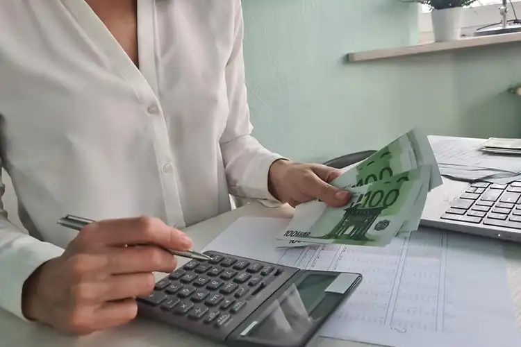 Mulher faz as contas com euros e uma calculadora.