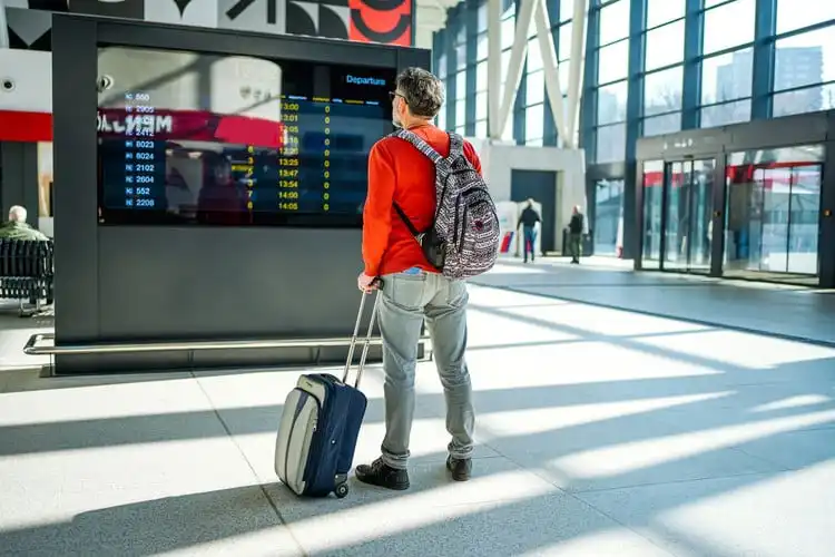 Homem olhando o painel de voos no aeroporto. 