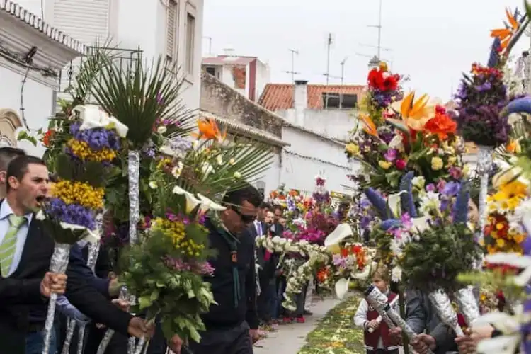 Homens de terno carregam flores na Procissão das Flores, no Algarve