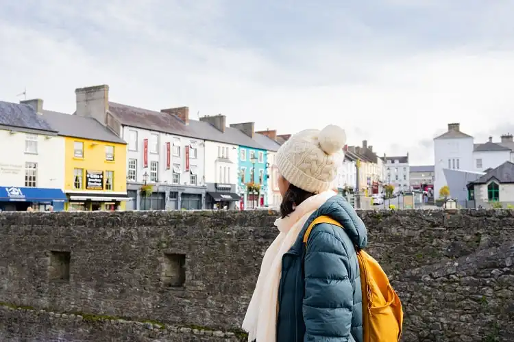 Mulher em Dublin, de mochila, olhando prédios da cidade.