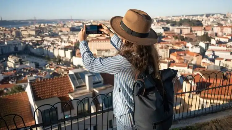 Mulher utilizando um chip Vodafone no celular para fotografar Lisboa, Portugal