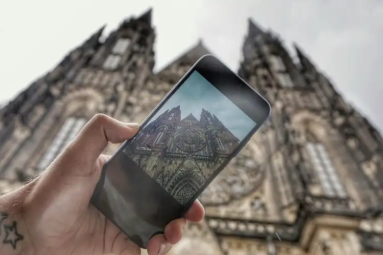 Pessoa tirando foto de um prédio histório europeu através de um smartphone preto