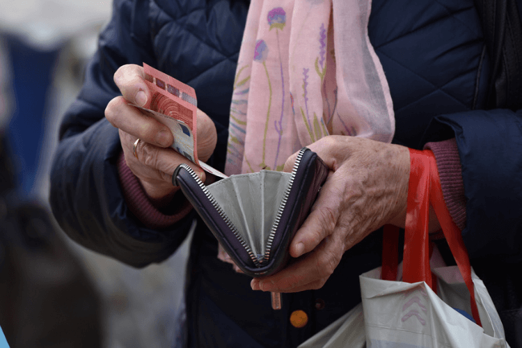 Mãos de uma senhora contando euros na carteira.