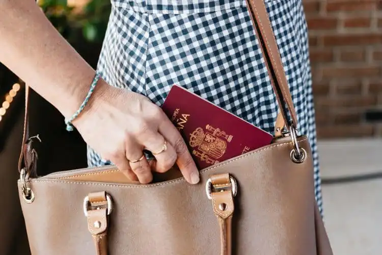 Mulher guarda passaporte espanhol na bolsa.