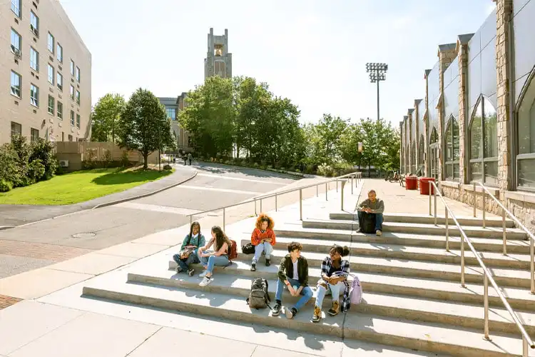 Grupo de estudantes repousa em uma escadaria da faculdade