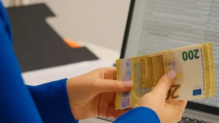 Pessoa contando cédulas de euro, após receber salário mínimo na França.