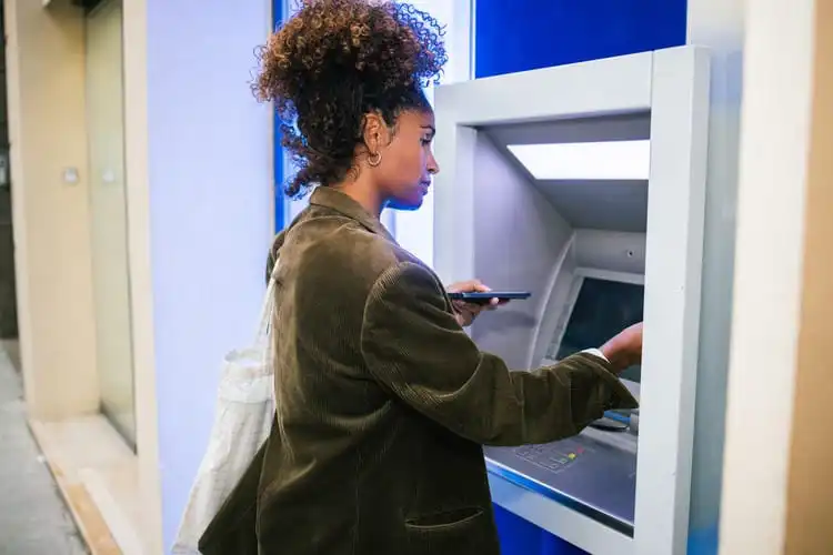 Mulher sacando dinheiro da sua conta Nomad Global no caixa eletrônico. 