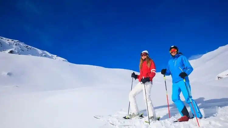 Homem e mulher com equipamento de ski nos alpes.
