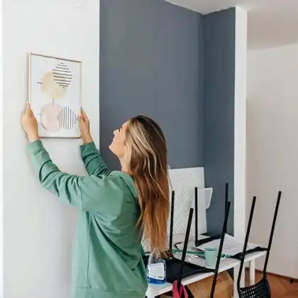 Mulher pendurando quadro na casa nova
