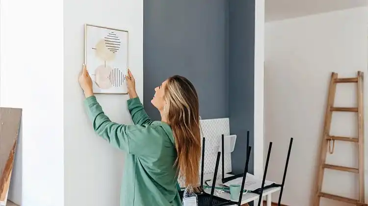 Mulher pendurando quadro na casa nova