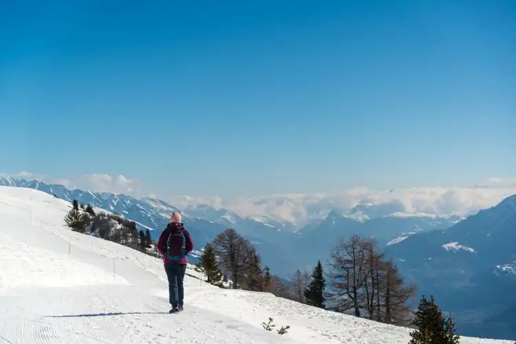 Mulher caminhando na neve na Suíça.