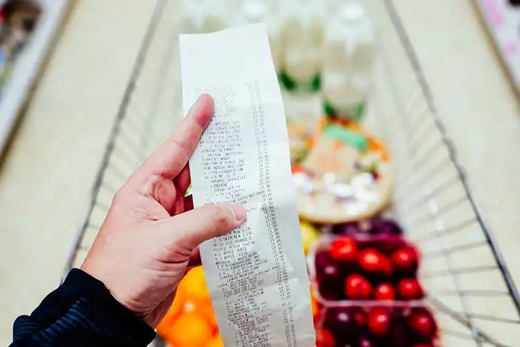 Homem confere o quanto pagou em compras no supermercado.