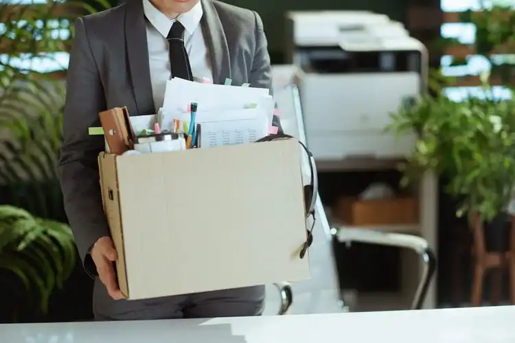 Homem desempregado segurando caixa com itens do escritório. 