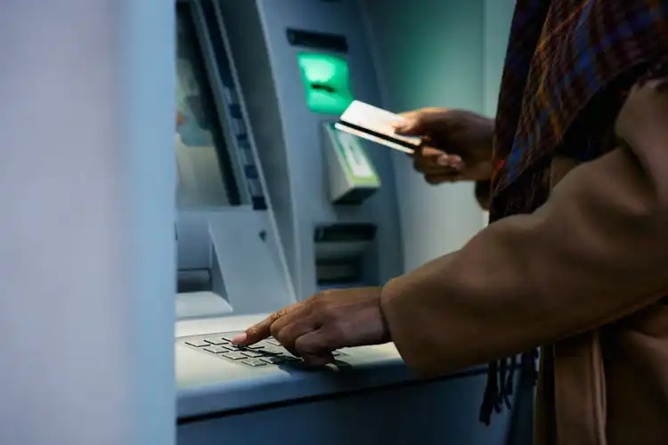 Mulher usando cartão de débito no caixa eletrônico