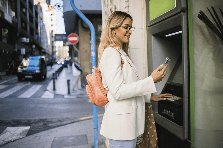 Mulher usando ATM após abrir conta em euros no Brasil