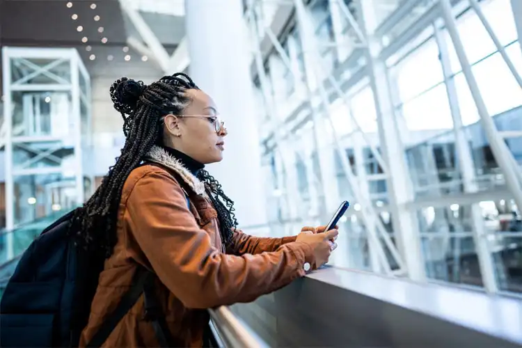 Mulher consulta seu celular em aeroporto.