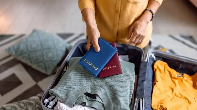 Homem arrumando mala e segurando dois passaportes