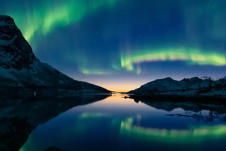 Paisagem da aurora boreal acima de um lago e colinas rochosas à noite em Tromso, Noruega