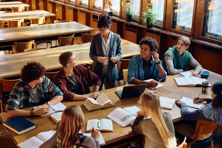 Grupo de alunos estudando com auxílio de professora em universidade da Irlanda.