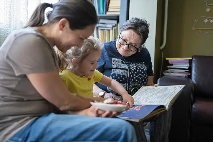 Três gerações de mulheres vendo um livro