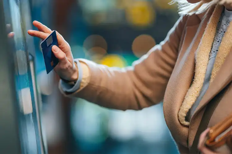 Mulher utiliza caixa eletrônico para fazer retirada de dinheiro.