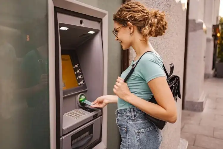 Mulher fazendo saque de dinheiro no caixa eletrônico. 